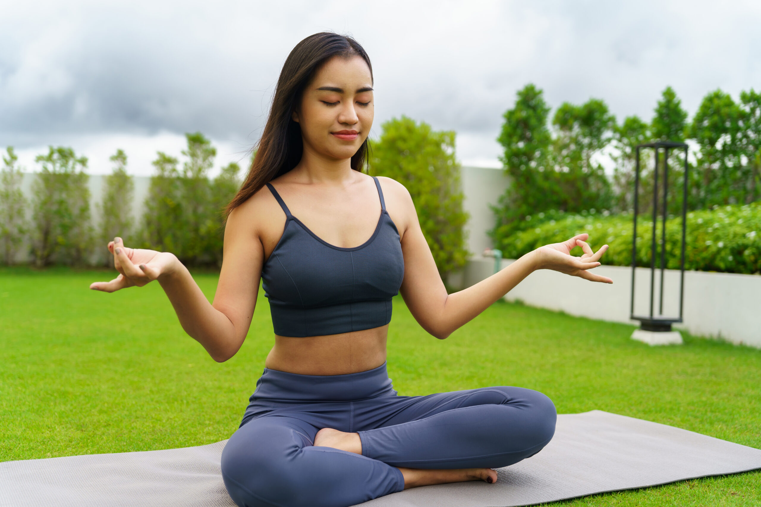 Beautiful confident asian woman practices yoga in green park
