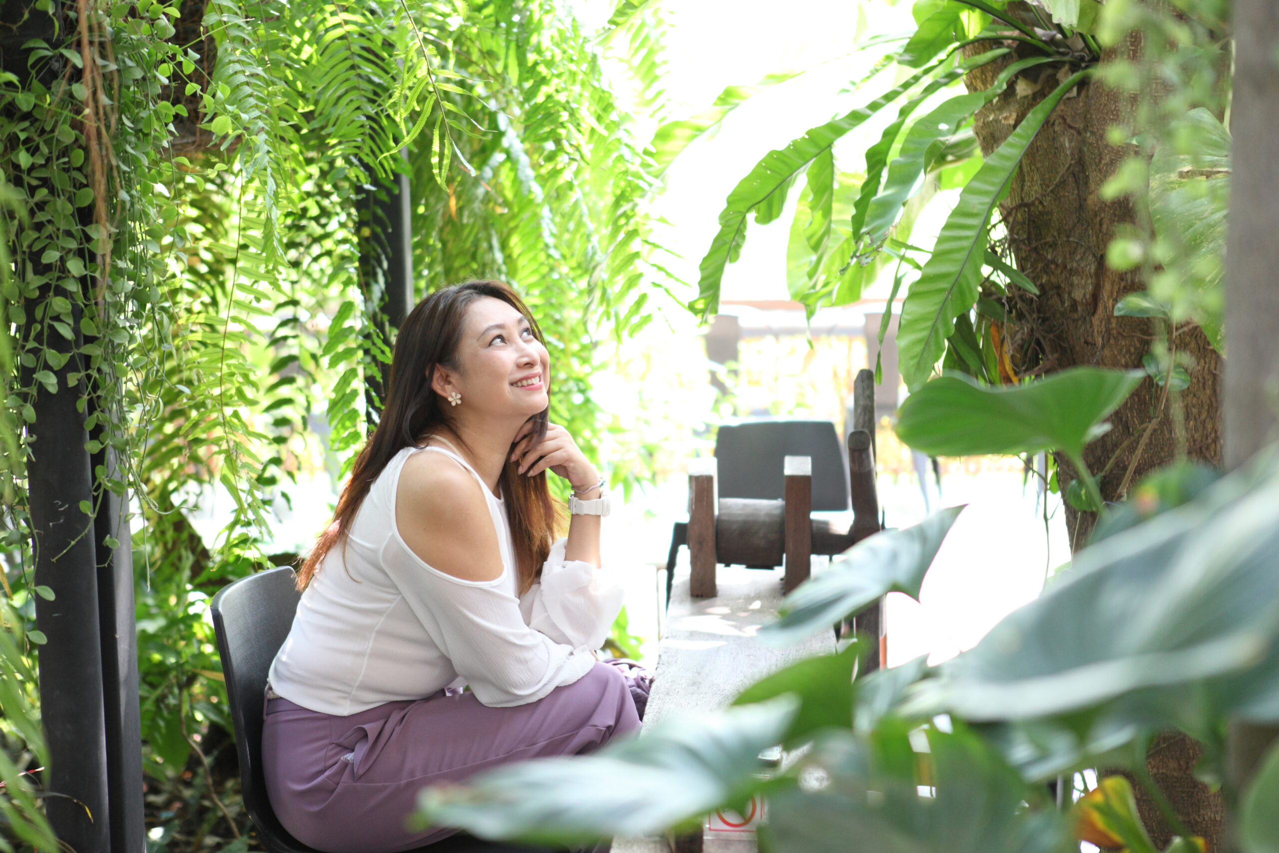 woman relaxing enjoying nature furniture on outdoor patio living room. Young woman sitting on chair in green garden terrace , Home lifestyle , resort